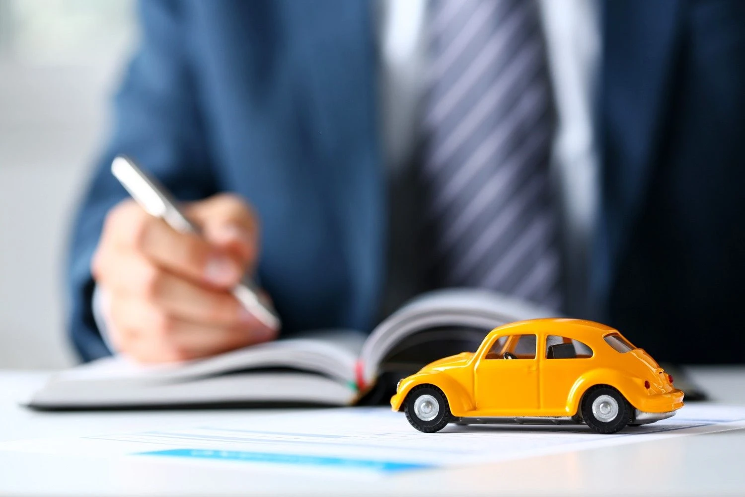 Small yellow car model resting on policy paperwork